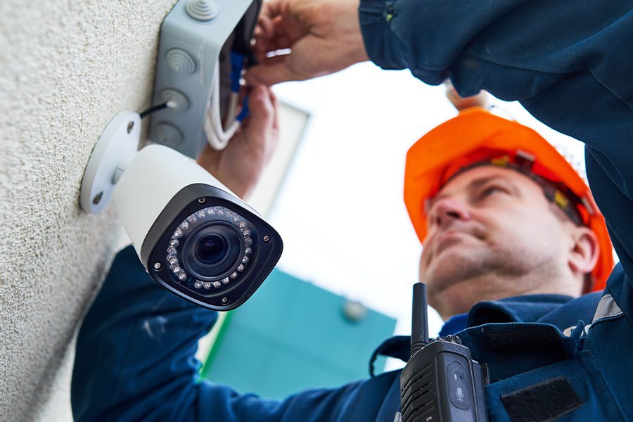 Alarm Contractor Insurance - Alarm Technician Worker Installing Video Surveillance Camera on a Wall